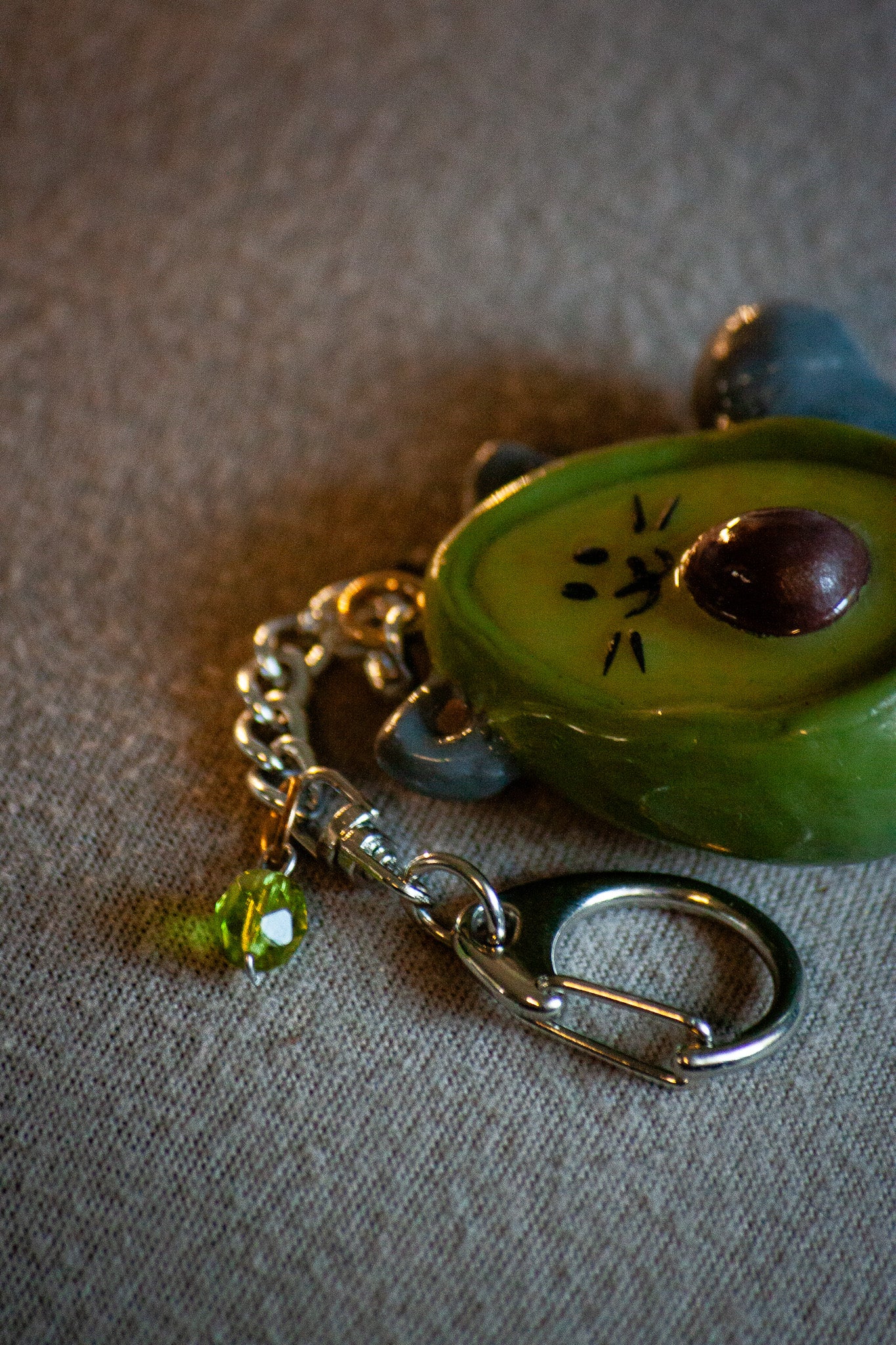 chain with a green small green circular charm from a cat-avocado shaped keychain 